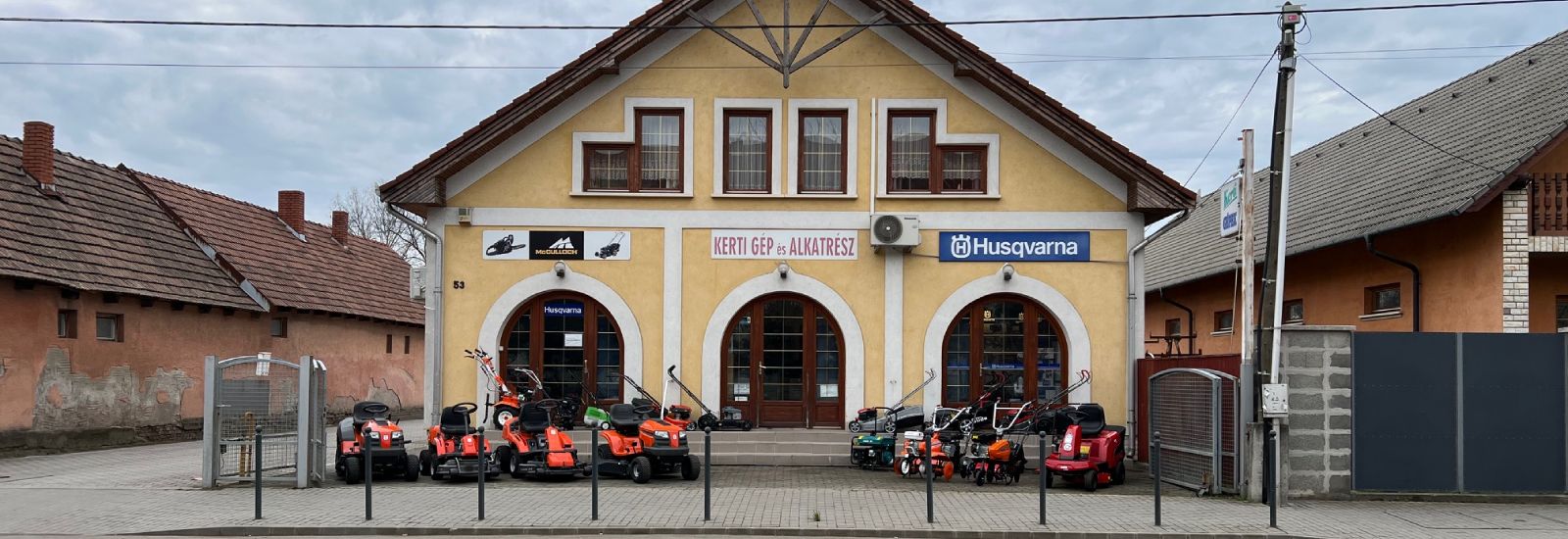 Husqvarna szaküzlet Hatvan, Horváth Mihály út 53. – az üzlet homlokzata fűnyíró traktorokkal és fűnyírókkal