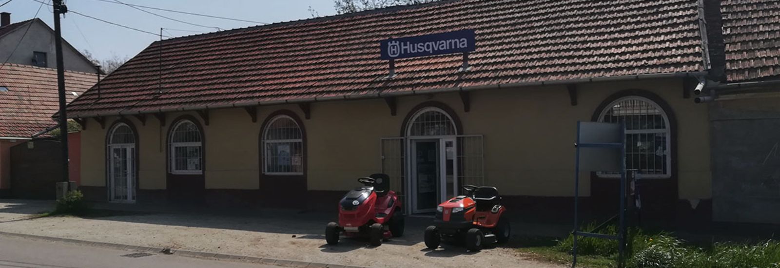Husqvarna szaküzlet Heves, Fő út 19. – a bolt íves ablakos homlokzata, előtte fűnyíró traktorok